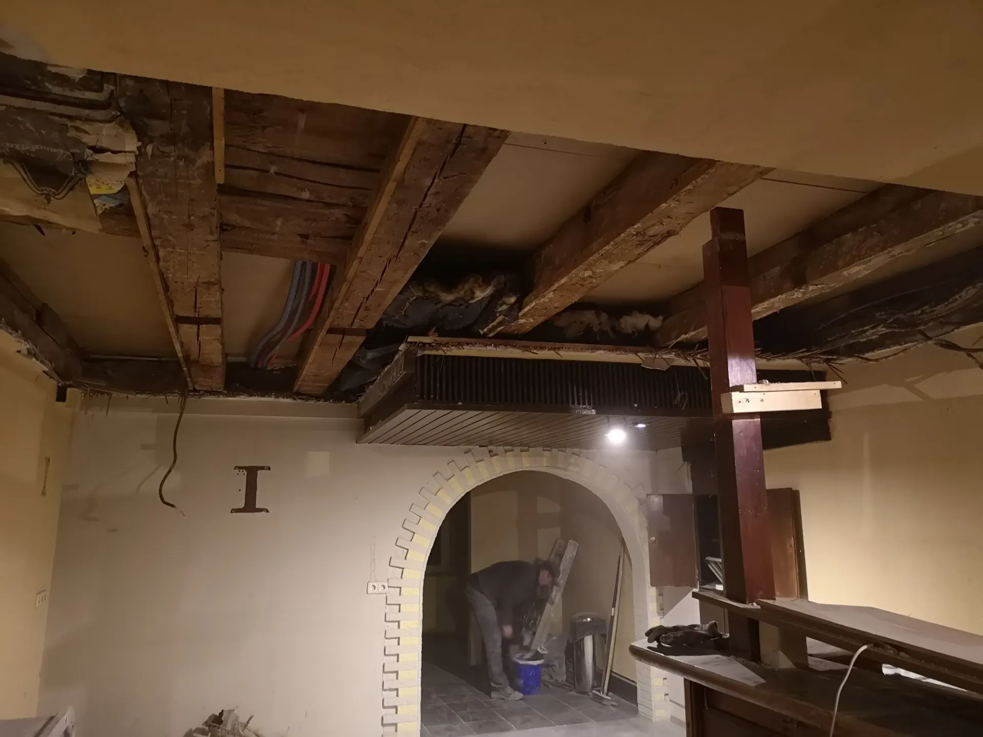 Geöffnete Holzbalkendecke in einem Altbau mit gemauertem Rundbogen