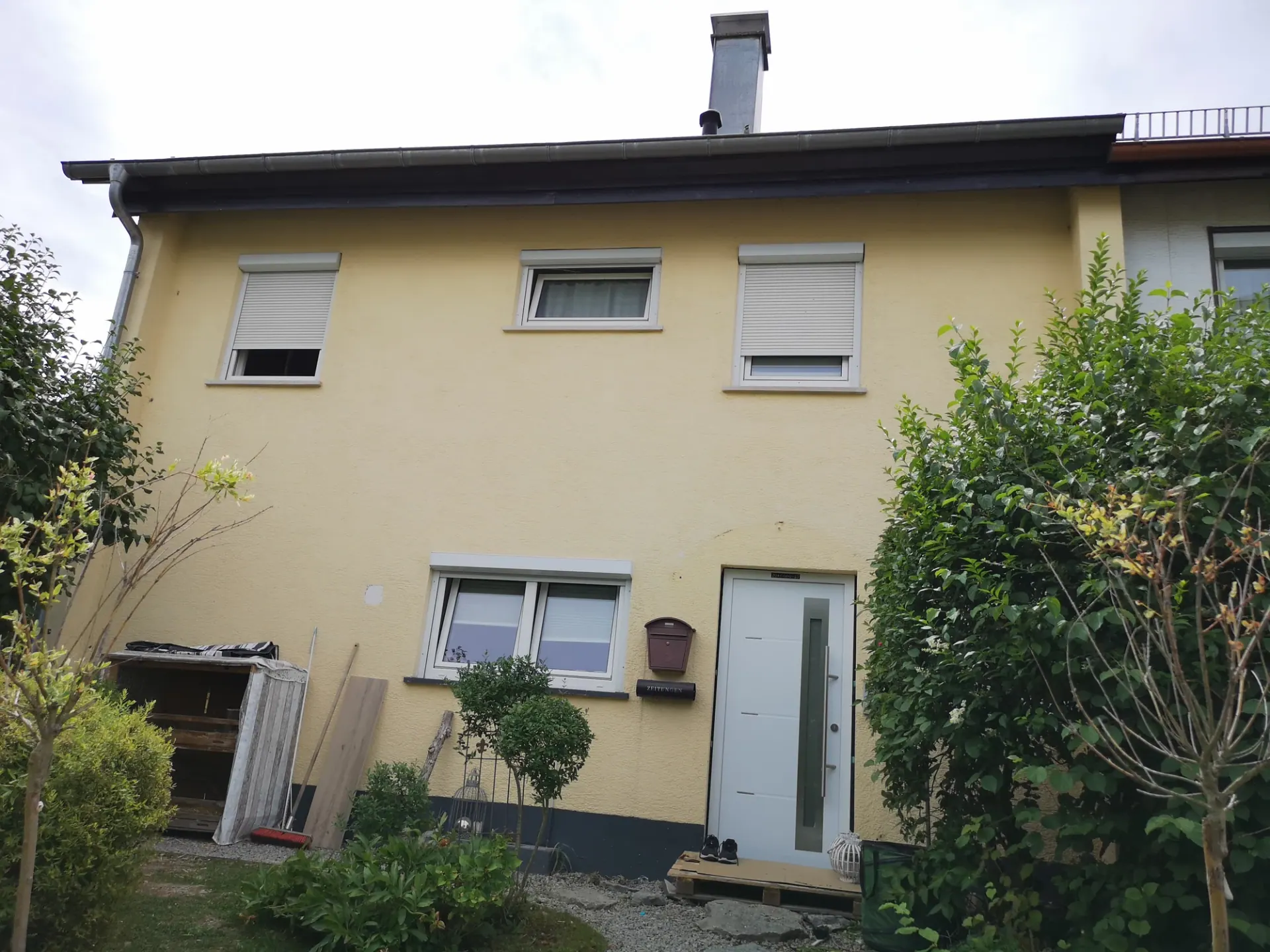 Gelbe Gartenseite eines Wohnhauses vor dem neuen Anstrich