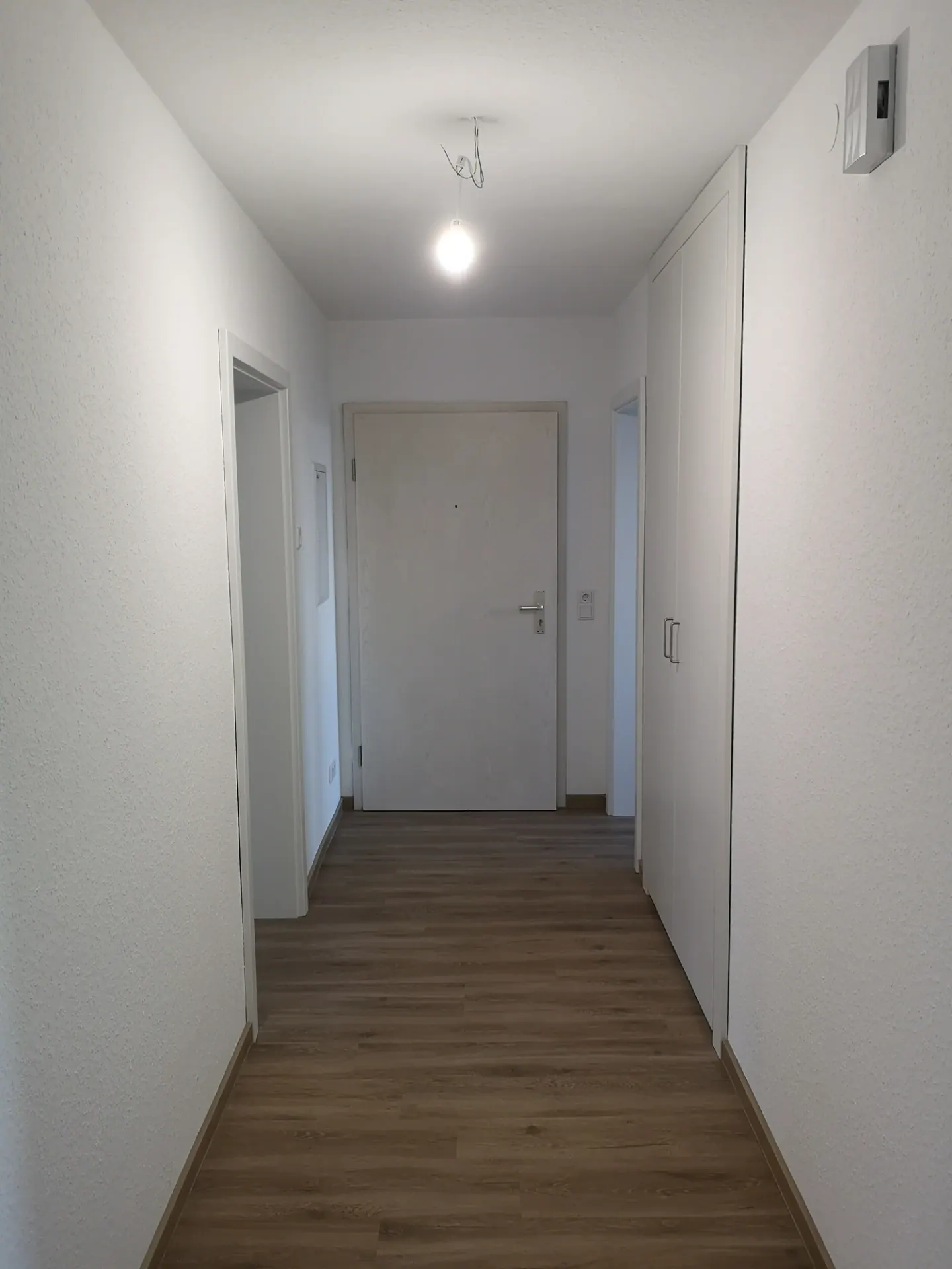 Flur mit weißen Wänden und durchgehendem Boden in Holzoptik